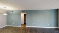 Located at 151 Century Dr in Greenville, SC, this single-floor unit offers a well-organized layout designed for comfortable everyday living. The living area is a standout space, featuring rich dark hardwood-style flooring and a soothing blue-grey accent wall that adds a touch of color and character. A large sliding glass door with vertical blinds fills the room with natural light and provides access to the outdoors. The open entryway flows seamlessly from the front door into the living space, maintaining a clean and connected feel throughout. The galley-style kitchen is efficiently designed with white cabinetry lining both sides, grey laminate countertops, a stainless steel sink, and black appliances including a full-size refrigerator and dishwasher. A ceiling light fixture brightens the space, making it functional and practical. The bedroom is carpeted for warmth and comfort, featuring neutral tones, a window with blinds that invites natural light, and access to a walk-in closet with built-in shelving for ample storage. The bathroom includes a vanity with a white basin sink, grey countertop, and a large mirror, paired with consistent hardwood-style flooring that ties the space together. Textured ceilings and clean white baseboards are consistent throughout, contributing to a tidy, cohesive aesthetic.