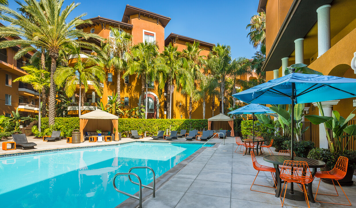 Resort-style pool with lounge chairs and covered tables - Palazzo East Apartments