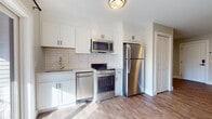 Located at 969 Hopmeadow St in Simsbury, Connecticut, this single-floor unit offers a thoughtfully designed layout with modern finishes throughout. The kitchen is a standout feature, outfitted with crisp white shaker-style cabinetry, a classic subway tile backsplash, and a full suite of stainless steel appliances including a refrigerator, electric range, built-in microwave, and dishwasher. Warm wood-look luxury vinyl plank flooring runs seamlessly throughout the unit, providing both durability and a cohesive aesthetic. The open living area is bright and airy, framed by neutral-toned walls and clean white baseboards, creating a versatile canvas for any furnishing style. A dedicated entryway with a solid panel door and keypad entry provides a welcoming and secure point of arrival. The bathroom continues the modern design language with floor-to-ceiling white rectangular tile surrounding a full soaking tub and tub-shower combo, complemented by sleek chrome fixtures. A separate vanity area with dark cabinetry adds a refined contrast. The overall ambiance of the unit is clean, contemporary, and move-in ready, making it an excellent space in the heart of Simsbury.