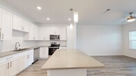 Located at 1911 Waterway Cir in Middleburg, FL, this thoughtfully designed one-bedroom, two-bathroom home offers a bright, modern living experience on a single floor. Light wood-style flooring runs consistently throughout, tying the spaces together with a clean, cohesive aesthetic.

The open-concept kitchen and living area serves as the heart of the home. The kitchen is outfitted with white shaker-style cabinetry, warm-toned quartz countertops, stainless steel appliances including a range, over-the-range microwave, and dishwasher, and a spacious island with pendant lighting overhead. The layout flows seamlessly into the living room, which benefits from multiple windows that fill the space with natural light, a ceiling fan, and direct access to an exterior door.

The primary bedroom is a comfortable retreat, featuring a ceiling fan, natural light from a set of windows, and access to a generously sized walk-in closet outfitted with wire shelving for ample storage. The bathrooms are well-appointed with white vanity cabinetry, warm-toned countertops, framed mirrors, and wood-style flooring that maintains the home's consistent design language. Clean white walls throughout contribute to the open, airy ambiance of the entire space.