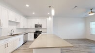 Located at 1911 Waterway Cir in Middleburg, FL, this thoughtfully designed one-bedroom, two-bathroom home offers a bright, modern living experience on a single floor. Light wood-style flooring runs consistently throughout, tying the spaces together with a clean, cohesive aesthetic.

The open-concept kitchen and living area serves as the heart of the home. The kitchen is outfitted with white shaker-style cabinetry, warm-toned quartz countertops, stainless steel appliances including a range, over-the-range microwave, and dishwasher, and a spacious island with pendant lighting overhead. The layout flows seamlessly into the living room, which benefits from multiple windows that fill the space with natural light, a ceiling fan, and direct access to an exterior door.

The primary bedroom is a comfortable retreat, featuring a ceiling fan, natural light from a set of windows, and access to a generously sized walk-in closet outfitted with wire shelving for ample storage. The bathrooms are well-appointed with white vanity cabinetry, warm-toned countertops, framed mirrors, and wood-style flooring that maintains the home's consistent design language. Clean white walls throughout contribute to the open, airy ambiance of the entire space.