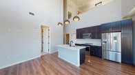 Located along South Cascade Avenue in Colorado Springs, this contemporary two-story residence offers an impressive blend of modern design and mountain living. The main level centers around a dramatic open-concept kitchen and living area, highlighted by soaring double-height ceilings that create an airy, expansive atmosphere. The kitchen is outfitted with dark navy cabinetry, stainless steel appliances, a white quartz waterfall island, and a geometric tile backsplash, all illuminated by stylish pendant lighting. Warm hardwood-style flooring runs throughout the main living areas, complementing the clean, modern aesthetic. Floor-to-ceiling windows flood the space with natural light and frame breathtaking panoramic views of the surrounding mountains and cityscape. The upper level features a bright open loft corridor overlooking the main floor, with continuous mountain views through expansive windows. Bedrooms are carpeted for comfort and offer generous closet space, with tall windows maintaining the connection to the outdoors. Bathrooms are finished with marble-style tile surrounds, dark matte hardware, and dark vanity cabinetry paired with illuminated mirrors. A staircase with modern metal railings connects the two levels, tying together the cohesive, upscale design throughout.