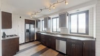 Located at 1445 E Broad St in Columbus, Ohio, this two-floor property offers a compelling mix of functional design and architectural character. The kitchen is well-appointed with dark espresso cabinetry, granite countertops, white tile backsplash, and stainless steel appliances including a gas range, built-in microwave, dishwasher, and a side-by-side refrigerator. Track lighting and multiple windows allow natural light to fill the space while framing views of the surrounding cityscape.

The living areas span both floors, featuring a combination of tile and carpeted flooring. One main room showcases a distinctive marble fireplace surround, textured wall treatments, and panoramic windows with broad city views. An interior staircase with decorative metal railings connects the levels, with stepped architectural details adding visual interest to the open layout.

The bathrooms display bold vintage character — one features deep blue tile from floor to ceiling with a soaking tub, while another is finished in warm terracotta tiling with an inset soaking tub and classic octagonal floor tiles. A dedicated laundry area includes a full-size washer and dryer. Carpeted bedrooms offer generous closet space and windows with elevated city views, completing this uniquely detailed multi-floor urban property.