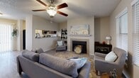This single-floor unit offers a thoughtfully arranged layout comprising a combined kitchen and living room, a dedicated office, one bedroom, and one full bathroom. The living room serves as the central gathering space, highlighted by a tiled fireplace with a white mantle, wood-look flooring, and two large windows that admit generous natural light. A ceiling fan overhead enhances comfort, while an open pass-through visually connects the living area to the kitchen.

The kitchen is equipped with dark wood cabinetry, light granite-style countertops, and black appliances including a range, refrigerator, and dishwasher. Wood-look flooring continues throughout, and a window above the sink brings in additional daylight.

The bedroom features carpet flooring, a ceiling fan, a sliding double-door closet, and a window with a built-in ledge. The office, also carpeted, includes a ceiling fan and a closet, offering flexibility for remote work or additional storage.

The bathroom is finished with wood-look flooring, a vanity with granite-style counters, and a shower-tub combination. Neutral tones and a textured ceiling are consistent throughout the unit, contributing to a cohesive, low-maintenance aesthetic.