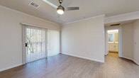 Located in Mesa, Arizona, this thoughtfully designed one-bedroom, one-bathroom residence offers a comfortable and functional single-floor layout. Light-toned luxury vinyl plank flooring flows throughout the entire unit, creating a cohesive and clean aesthetic.

The combined kitchen and living area serves as the heart of the home. The living space is bathed in natural light through a large sliding glass door framed by vertical blinds, which opens to an outdoor view of lush greenery. A ceiling fan with a built-in light fixture and crown molding add a refined touch overhead. The galley-style kitchen is well-equipped with white shaker cabinetry, light quartz countertops, and black appliances including a range, over-the-range microwave, refrigerator, and dishwasher.

The bedroom is a comfortable retreat, featuring a large window with horizontal blinds that invite ample natural light and treetop views. The bathroom is clean and modern, showcasing a white vanity with quartz countertop, a full tub-shower combo with white tile surround, and wood-look flooring. A dedicated laundry area with a full-size washer and dryer adds everyday convenience. The unit also includes a closet and a hallway that connects all spaces efficiently.