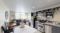 Located on the sixth floor at 434 SW College St in Portland, Oregon, this one-bedroom, one-bathroom apartment offers a thoughtfully designed layout that maximizes every square foot. The living room is bright and welcoming, featuring a large window that frames views of the surrounding cityscape and lush hillside. The open arrangement accommodates a comfortable seating area alongside a dining space, with a round decorative mirror adding depth to the room.

The kitchen is efficiently configured with stainless steel appliances, including a gas range, microwave, and dishwasher. Dark open shelving contrasts with light countertops, creating a modern, functional workspace ideal for everyday cooking.

The bedroom is a calm, well-lit retreat highlighted by floor-to-ceiling windows that offer expansive views of Portland's skyline and West Hills. Textured carpet flooring adds warmth, while recessed lighting keeps the space feeling clean and contemporary.

The bathroom is accessed via a sliding door and features a dark wood vanity with a light stone countertop, a shower with a striped curtain, and a clean, neutral color palette throughout.

Overall, the apartment carries a modern urban aesthetic with consistent finishes, natural light, and elevated views that make the most of its downtown Portland location.