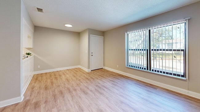 Sala de estar luminosa y acogedora con grandes ventanales y elegantes pisos de madera, ideal para relajarse y entretenerse. - Chateau of Tampa