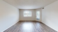Located in St. Louis Park, MN, this one-bedroom, one-bathroom unit offers a well-organized single-floor layout designed for comfortable everyday living. The spacious living room is a standout feature, showcasing rich wood-look flooring that extends throughout the main living areas, neutral-toned walls, and a textured ceiling. A large window and a glass-panel exterior door flood the room with natural light while providing direct outdoor access, creating a bright and open atmosphere. The living room flows naturally toward the kitchen, which is connected via a pass-through counter and opening — ideal for an inclusive feel between cooking and living spaces. The kitchen features warm wood cabinetry, stainless steel appliances including a range and over-the-range microwave, and a clean countertop surface. The bedroom offers plush carpeting, a window with natural light, and generous wall space, providing a quiet and comfortable retreat. The bathroom is well-appointed with a wood-toned vanity, ample cabinet storage, a white countertop, and a full tub-shower combination. A dedicated hallway connects the rooms efficiently, and a utility room adds practical storage and functional space. Overall, the unit presents a clean, neutral palette throughout.