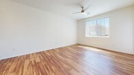 Located in Glendale, Arizona, this single-floor, one-bedroom, one-bathroom unit offers a well-organized layout with distinct living, cooking, sleeping, and storage spaces. The open living room is bright and airy, featuring warm wood-look flooring, a ceiling fan, and a large window with vertical blinds that allows abundant natural light to flow in, along with access to an exterior door. The kitchen is well-appointed with honey-toned wood cabinetry, granite-look countertops, white appliances including a refrigerator, range, dishwasher, and microwave, as well as a central island that provides additional prep space and storage. Track lighting overhead adds a functional, modern touch. The bedroom is comfortably sized, finished with soft carpeting and a window that brings in natural light. It connects directly to a dedicated closet, offering practical storage. The bathroom continues the wood-look flooring found throughout the main living areas and includes a vanity with granite-look countertops, warm wood cabinetry, a large mirror, and accessibility-friendly grab bars. Clean white walls and neutral tones throughout the unit create a cohesive, move-in-ready atmosphere.