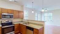 Located at 1100 Deer Harbor Dr in Garner, North Carolina, this single-floor residence offers a well-designed, open-concept layout that seamlessly connects the kitchen and living areas. The kitchen is a standout feature, showcasing warm-toned shaker-style cabinetry, granite countertops, and a full suite of stainless steel appliances including a refrigerator, range, microwave, and dishwasher. A peninsula with pendant lighting overhead serves as a natural divider between the kitchen and the living area, enhancing both function and style. Light wood-style flooring runs through the kitchen and connected spaces, adding warmth to the interior. The living area is bright and airy, benefiting from multiple windows dressed with horizontal blinds and a ceiling fan that promotes comfortable airflow. Bedrooms feature plush wall-to-wall carpeting, ceiling fans, and natural light from windows, providing a comfortable and restful environment. The bathroom is clean and functional, with wood-toned vanity cabinetry, a well-lit mirror, and light hardwood-style flooring. Neutral wall tones throughout the home create a cohesive, move-in-ready aesthetic. The thoughtful floor plan, as revealed in the dollhouse view, reflects an efficient use of space with clear separation between living, sleeping, and bathing areas.