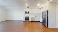 Located on the iconic Wilshire Boulevard in Los Angeles, this modern one-bedroom, one-bathroom unit offers a thoughtfully designed layout across a single floor. Warm hardwood-style flooring runs throughout the entire space, creating a cohesive and inviting atmosphere.

The open-concept kitchen and living area serves as the heart of the unit. The kitchen is well-appointed with sleek white cabinetry, light countertops, and a full suite of stainless steel appliances including a refrigerator, dishwasher, range, and built-in microwave. Recessed lighting illuminates the space efficiently.

The bedroom is a comfortable, bright retreat featuring a large sliding glass door with horizontal blinds that opens to a private balcony with outdoor views. A dedicated walk-in closet off the bedroom provides generous storage with double hanging rods and a full shelving unit, offering excellent organization capacity.

The bathroom is finished with large-format neutral stone-look tile lining the tub and shower surround, complemented by matching floor tile and clean chrome fixtures, lending a spa-like feel.

A hallway connects the main living area to the private spaces, and the overall design emphasizes clean lines, a neutral color palette of crisp whites and warm wood tones, and a modern aesthetic suited to urban living in the heart of Los Angeles.