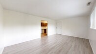 Located at 90 Juanita Ct in Springboro, Ohio, this two-bedroom, single-floor home offers a well-organized and efficient layout. The interior is finished with light-toned luxury vinyl plank flooring throughout, complemented by crisp white walls and clean white trim, creating a bright and cohesive aesthetic across all rooms.

The living room is an open, generously sized space that connects directly to the galley-style kitchen. The kitchen features rich dark-stained wood cabinetry lining both walls, white laminate countertops, a built-in sink, and white appliances including an electric range and refrigerator — offering ample storage and workspace in a functional corridor layout.

The spacious primary bedroom provides a comfortable retreat, complete with a closet. The second bedroom is well-proportioned and includes a window with blinds that allows natural light and views of the surrounding greenery. Both bedrooms share access to the home's bathroom, which is visible from the bedroom corridor.

Throughout the home, the neutral color palette and consistent flooring lend a clean, move-in-ready feel. The layout, as seen in the dollhouse view, is compact yet practical, with rooms arranged to maximize usability within the single-story footprint. This home is ideal for those seeking straightforward, low-maintenance living in Springboro.