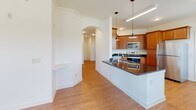Located at 200 Greenfield Ln in Rockingham, Virginia, this single-floor residence offers a thoughtfully designed open-concept layout that seamlessly connects the kitchen, dining, and living areas. The kitchen is a standout feature, showcasing warm wood cabinetry, dark granite countertops, a full suite of stainless steel appliances including a range, microwave, dishwasher, and refrigerator, and pendant lighting above the breakfast bar peninsula. An elegant arched doorway leads from the kitchen into the living and dining areas, where large windows flood the space with abundant natural light and offer views of the surrounding greenery. Durable wood-look flooring runs throughout the main living areas, adding warmth and continuity to the design. The bedrooms are carpeted for comfort, each equipped with ceiling fans, and offer generous proportions with ample closet space. One bedroom features a spacious walk-in closet with multi-level wire shelving. The bathrooms are well-appointed with rich wood vanities, granite-toned countertops, large mirrors, and wood-look flooring. One bathroom includes a soaking tub and shower combination, while another offers a streamlined layout. The overall ambiance is clean, bright, and move-in ready.