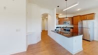 Located at 200 Greenfield Ln in Rockingham, Virginia, this single-floor residence offers a thoughtfully designed open-concept layout that seamlessly connects the kitchen, dining, and living areas. The kitchen is a standout feature, showcasing warm wood cabinetry, dark granite countertops, a full suite of stainless steel appliances including a range, microwave, dishwasher, and refrigerator, and pendant lighting above the breakfast bar peninsula. An elegant arched doorway leads from the kitchen into the living and dining areas, where large windows flood the space with abundant natural light and offer views of the surrounding greenery. Durable wood-look flooring runs throughout the main living areas, adding warmth and continuity to the design. The bedrooms are carpeted for comfort, each equipped with ceiling fans, and offer generous proportions with ample closet space. One bedroom features a spacious walk-in closet with multi-level wire shelving. The bathrooms are well-appointed with rich wood vanities, granite-toned countertops, large mirrors, and wood-look flooring. One bathroom includes a soaking tub and shower combination, while another offers a streamlined layout. The overall ambiance is clean, bright, and move-in ready.