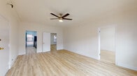 Located in the Koreatown neighborhood of Los Angeles, this single-floor unit at 750 S Mariposa Ave offers a thoughtfully updated interior with a cohesive blend of modern finishes and classic architectural character. Light hardwood flooring runs throughout the space, creating a bright and airy feel across all rooms.

The open living area is a standout, featuring a ceiling fan with integrated lighting and a striking exposed brick accent wall that adds warmth and texture. Natural light filters in through multiple windows dressed with blinds. The galley-style kitchen is well-appointed with slate-blue shaker cabinetry, granite-style countertops, a double stainless steel sink, and stainless steel appliances including an electric range and refrigerator.

The bedrooms are comfortably sized with clean white walls, hardwood floors, and ample natural light. One bedroom includes a mirrored sliding closet door providing access to a walk-in closet area, while another features a window-mounted AC unit.

The bathroom is finished with striking dark hexagonal floor tiles, crisp white walls, gold-tone hardware and fixtures, and a soaking tub, delivering a polished, contemporary aesthetic. The overall design balances modern updates with timeless details, making this a well-rounded urban residence.