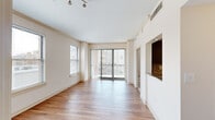 This single-floor residence offers a thoughtfully designed layout with a clean, contemporary aesthetic throughout. The open living area is a standout feature, bathed in natural light from large sliding glass doors that lead to a private balcony with outdoor views, complemented by an additional side window and track lighting overhead. Warm hardwood-style flooring flows through the main living spaces and hallways, creating a cohesive and inviting atmosphere.

The kitchen is outfitted with rich, dark espresso cabinetry, granite countertops, a decorative mosaic tile backsplash, and stainless steel appliances including a dishwasher, range, and microwave — combining style with everyday functionality. A pass-through opening connects the kitchen to the living area, enhancing the open feel.

The bedrooms feature plush carpeting and generous natural light from multiple windows with blinds. The primary bedroom is particularly well-appointed, boasting dual sliding closets for abundant storage. A secondary bedroom includes its own closet with elegant paneled doors.

The primary bathroom features a dark-framed vanity mirror, granite countertop, dark wood cabinetry, and a tiled tub-shower surround. A second full bathroom offers a clean, functional design with in-unit stacked washer and dryer conveniently tucked nearby.