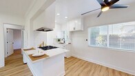Located at 15040 Leffingwell Rd in La Mirada, CA, this thoughtfully updated single-story home offers a cohesive, modern design across two bedrooms and one bathroom. Light wood vinyl flooring runs throughout the entire home, creating a warm and unified feel. The open kitchen is a standout feature, boasting white shaker cabinetry with black hardware, a white subway tile backsplash, quartz countertops, a gas range with stainless steel appliances, and a peninsula that doubles as a dining counter. Recessed lighting and a ceiling fan keep the space bright and comfortable. The kitchen flows naturally into the dining area, which is bathed in natural light from a large window with views of surrounding greenery. The living room is clean and airy, with crown molding, a ceiling fan, and a welcoming front entry. Both bedrooms are well-proportioned, each featuring ceiling fans and windows overlooking lush outdoor foliage. The primary bedroom includes floor-to-ceiling mirrored closet doors framed in black, paired with white built-in upper cabinetry for ample storage. The bathroom is elegantly finished with white subway tile, a glass-enclosed walk-in shower with black framing, and a white vanity with black fixtures, all tied together with wood-look flooring.