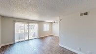 This single-story, one-bedroom, one-bathroom unit offers a well-organized layout across a modest but efficiently utilized floor plan. Wood-look plank flooring runs consistently throughout the space, lending a cohesive and clean aesthetic from room to room.

The living room serves as the central gathering area, highlighted by a sliding glass door fitted with vertical blinds that allow natural light to filter in while providing outdoor access. A ceiling fan overhead aids in air circulation, and neutral-toned walls with white baseboards contribute to a bright, open feel.

Adjacent to the living area, the galley-style kitchen is functional and neatly arranged, featuring white shaker-style cabinetry, dark laminate countertops, a stainless steel sink, and black appliances including a range and refrigerator. A flush-mount ceiling light provides direct illumination over the workspace.

The bedroom is a comfortably sized retreat with a wide window that brings in natural light. It features dual sliding-door closets with built-in shelving, offering practical storage solutions. Textured ceilings are present throughout the unit.

The bathroom includes a full tub-shower combination with tile surround, a toilet, and a vanity with a dark countertop, maintaining the consistent neutral palette found throughout the unit. A hallway connects the main rooms, completing the straightforward and functional layout.