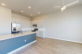 Located in Goodyear, Arizona, this two-story home offers a well-designed layout spread across two floors. The ground level houses an attached garage with automatic opener, direct interior access, and ample space for parking and storage. The main living area features light wood-look flooring, recessed lighting, and a ceiling fan, creating a bright and comfortable atmosphere. The kitchen is a standout feature, boasting crisp white shaker cabinets, a bold blue-accented island with a white quartz countertop and undermount sink, and a full suite of stainless steel appliances including a French door refrigerator, range, and microwave. Upstairs, the upper floor contains both bedrooms, each finished with plush carpet and ceiling fans. The spacious primary bedroom includes a sliding glass door opening to a private outdoor balcony, while the second bedroom features a large window for natural light. Two closets offer built-in shelving and hanging rods for organized storage. The three bathrooms are finished with light wood-look flooring, soft-close shaker vanities, and clean white countertops. A neutral, modern color palette flows throughout, giving the entire home a cohesive and move-in-ready feel.