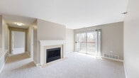Located at 1225 Deerfield Parkway in Buffalo Grove, Illinois, this two-bedroom, one-bathroom residence offers a well-designed single-floor layout with a comfortable and functional flow throughout. The open living room is a central highlight, featuring a classic wood-burning fireplace with a white tile surround and decorative mantel, neutral-toned carpet flooring, and soft taupe walls that create a warm, inviting atmosphere. A sliding glass door fills the space with natural light and provides direct access to a private balcony overlooking a wooded outdoor setting. The kitchen is outfitted with rich wood cabinetry, stainless steel appliances including a refrigerator, electric range, over-the-range microwave, and dishwasher, complemented by light countertops and wood-look vinyl plank flooring. A breakfast bar connects the kitchen to the main living area, enhancing the open feel. The spacious primary bedroom includes a generous walk-in closet with wire shelving, offering ample storage. The second bedroom is well-proportioned with its own closet. The full bathroom features tile flooring, a tub-shower combination, and warm wood vanity cabinetry. Throughout the residence, neutral tones and clean finishes create a cohesive and move-in-ready aesthetic.