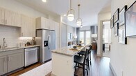Located in Frisco, TX, this well-appointed one-bedroom, one-bathroom residence offers a cohesive and modern design throughout its efficiently utilized single floor. The open-concept kitchen and living area serves as the heart of the home, where the kitchen impresses with granite countertops, gray shaker-style lower cabinets, light wood upper cabinetry, a subway tile backsplash, and a full suite of stainless steel appliances including a range, microwave, dishwasher, and refrigerator. Wood-look flooring flows throughout the main living areas, anchoring the bright and airy atmosphere. The living room is generously proportioned, featuring large double French doors that open to an outdoor balcony, allowing abundant natural light and views of the surrounding landscape. The bedroom offers plush carpeting, multiple windows with outdoor views, and a calm, neutral palette. Adjacent to the bedroom is a well-organized walk-in closet with built-in shelving and dual hanging rods. The bathroom is finished with a granite-topped vanity, gray cabinetry, wood-look flooring, and a full tub-shower combination. Clean white walls and consistent, contemporary finishes create a polished and cohesive ambiance throughout the entire space.