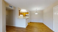 This single-story residence presents a practical and well-organized layout connecting its main living spaces in a cohesive flow. The living area is bright and open, featuring warm hardwood-style flooring and a sliding glass door fitted with vertical blinds that allows natural light to fill the room. A pendant light fixture defines the adjacent dining area, which connects seamlessly to the kitchen via a peninsula-style breakfast bar.

The kitchen is efficiently arranged in a galley configuration, equipped with warm-toned wood cabinetry, white appliances including a range and refrigerator, a built-in sink, and light countertops. A flush ceiling light and a separate entry door provide additional functionality to the space.

The bedrooms are carpeted for comfort, with neutral walls and ample natural light provided by large windows. One bedroom features a ceiling fan with a light fixture, while another includes mirrored sliding closet doors that enhance the sense of space. The bathroom is clean and straightforward, offering a full-size tub and shower combination with white tile surround, chrome fixtures, and hardwood-style flooring. Throughout the unit, neutral tones and clean finishes create a consistent, move-in ready ambiance.