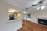 Located at 101 S Twin Creek Dr in Killeen, TX, this 2-bedroom, 2-bathroom residence offers a practical and comfortable single-floor layout. The open-concept living and kitchen area serves as the heart of the home, featuring rich hardwood-style flooring, a ceiling fan with light fixture, a wood-burning fireplace, and a sliding glass door that opens to a private patio. The kitchen is well-equipped with warm wood cabinetry, black appliances including a range, microwave, and refrigerator, light countertops, a double-basin sink, and a breakfast bar that provides additional seating and workspace. A skylight-style recessed ceiling detail adds a bright, inviting quality to the kitchen. Both bedrooms are carpeted and include ceiling fans and dedicated closet space — the primary bedroom features dual closets, while the second bedroom offers a walk-in closet. Each bathroom includes a full tub-shower combination with white tile surround. Additional spaces include a hallway, a laundry area, and ample storage. Textured ceilings are consistent throughout the home, contributing to its classic residential character.