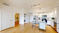 Located in Miami Lakes, FL, this modern 1-bedroom, 1-bathroom residence offers a clean, contemporary design across a thoughtfully arranged single floor. Light wood flooring flows seamlessly throughout the entire space, creating a warm and cohesive aesthetic. The open-concept living and kitchen area is bright and airy, anchored by a sleek white kitchen featuring flat-panel cabinetry extending to the ceiling, stainless steel appliances including a French door refrigerator, electric range, microwave, and dishwasher, plus a central island with a minimalist metal frame — ideal for dining or casual use. Track lighting overhead adds a modern touch. A stacked in-unit washer and dryer is conveniently tucked into a dedicated nook adjacent to the kitchen. The living area opens directly to a private balcony through a large sliding glass door, inviting natural light and outdoor views. The bedroom is well-proportioned, featuring a black-framed window overlooking greenery and access to a dedicated walk-in closet. The bathroom is finished with clean white subway tile, a glass-enclosed walk-in shower, a white vanity with stone countertop, and wood-look flooring that continues the space's unified design language.