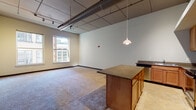 Located in the heart of Detroit, MI 48226, this studio loft offers a compelling blend of urban industrial design and functional living. The single-floor layout maximizes an open-concept living space, where the kitchen and living area flow seamlessly together beneath dramatic elevated ceilings that showcase exposed ductwork and track lighting — hallmarks of classic loft-style architecture.

The kitchen is well-appointed with warm wood cabinetry, dark granite countertops, a full suite of stainless steel appliances including a refrigerator, electric range, microwave, and dishwasher, as well as a central island that provides additional prep and dining space. A pendant light overhead adds a warm, focused glow to the cooking area.

The generous open living space features carpeted flooring and is bathed in natural light from large windows that frame views of the surrounding Detroit cityscape, giving the space an airy, connected-to-the-city feel.

The full bathroom includes tile flooring, grab bars, and a practical layout, with the added convenience of an in-unit washer tucked nearby. The overall ambiance is modern and urban, with industrial character details that give this Detroit studio a distinctive loft personality.