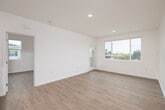 Located at 2039 East 8th Street in National City, CA, this well-designed 2-bedroom, 2-bathroom unit offers a clean, modern aesthetic throughout its single-floor layout. Warm-toned luxury vinyl plank flooring flows consistently across every room, complementing the crisp white walls and creating a bright, cohesive atmosphere.

The open-concept living and dining area is generously sized, with large windows that invite abundant natural light and provide views of the surrounding neighborhood. A glass door leads to a private balcony, extending the living space outdoors. The kitchen is thoughtfully appointed with white shaker-style cabinetry reaching to the ceiling for maximum storage, stainless steel appliances including a refrigerator, electric range, and microwave, a marble-look tile backsplash, and a kitchen island with a quartz-style countertop and an integrated sink.

A hallway connects the main living areas to the two bedrooms, each offering generous closet space. The primary bedroom is a comfortable retreat with a dedicated window framing outdoor views. Both bathrooms feature a clean, minimalist design with white cabinetry, tub-shower combinations, and matching vinyl flooring. A dedicated laundry area and utility room add practical convenience, rounding out this efficiently planned, move-in-ready home.