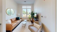 Located at 230 Beal St in Hingham, Massachusetts, this single-floor residence offers a thoughtfully designed layout with modern finishes throughout. The open-concept living area features rich hardwood-style flooring, neutral walls, and large windows that flood the space with natural light and offer pleasant outdoor views of the surrounding greenery. The living room comfortably accommodates a seating arrangement centered around a bright, sun-lit window, creating a welcoming and airy atmosphere.

The kitchen is a standout feature, outfitted with crisp white shaker cabinetry, dark quartz countertops, a hexagonal and subway tile backsplash, and a full suite of stainless steel appliances including a gas range with a wall-mounted hood, a side-by-side refrigerator, and a dishwasher — ideal for both everyday cooking and entertaining.

The primary bedroom is generously proportioned with soaring ceilings, light-toned walls, and access to a walk-in closet with built-in shelving. A secondary bedroom offers plush carpeting and a large window with outdoor views. The bathroom is clean and contemporary, featuring white cabinetry with dark countertops, a glass-enclosed shower with white tile surround, neutral floor tile, and floating wood shelves for added storage and style.