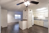 Located at 10517 Ashwood Dr in El Paso, Texas, this two-story home blends functional design with distinctive architectural character. A recurring theme throughout the space is the white-painted exposed brick, which appears as bold accent walls in the living areas and bedrooms, lending a clean yet textured aesthetic to the interior.

The main living area features durable wood-look flooring and is anchored by a peninsula-style counter that separates it from the kitchen. Ceiling fans provide comfort throughout. A staircase connects the two levels, and the layout flows naturally between living and dining zones.

The kitchen is well-equipped with white cabinetry, a subway-tile brick backsplash, gray laminate countertops, and a full suite of white appliances including a refrigerator, dishwasher, and electric range. Ample cabinet storage lines the walls from counter to ceiling.

The bedrooms are carpeted for comfort and feature the signature white brick accent walls alongside ceiling fans and windows with blinds that allow for natural light. Closet access is available within the bedroom areas.

Bathrooms are finished with wood-look flooring, a vanity with gray speckled countertops and gold-toned fixtures, a large mirror, and clean white walls. A separate water closet provides additional privacy. Textured ceilings are consistent throughout the home, adding to its classic character.