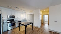 Located at 8383 Brandt Pike in Huber Heights, Ohio, this single-floor unit offers a well-designed, contemporary layout with a cohesive blend of modern finishes throughout. The open-concept kitchen and adjoining dining area serve as the heart of the space, showcasing white shaker-style cabinetry with matte black hardware, granite-speckled countertops, and a full suite of stainless steel appliances including a refrigerator, electric range, microwave, and dishwasher. Track lighting illuminates the kitchen, while a pendant light adds a refined focal point above the dining area. Wood-look plank flooring extends through the kitchen, dining, and living areas, lending warmth and visual continuity.

The living room is generously proportioned, with clean white walls, and benefits from natural light via large windows and a sliding glass door with vertical blinds. The bedrooms are carpeted for comfort, each featuring windows that bring in natural light and views of the surrounding area. A spacious walk-in closet equipped with wire shelving systems offers substantial storage capacity.

The bathroom is appointed with a granite-top vanity, framed mirror, industrial-style lighting fixtures, and a glass-enclosed shower, all set on wood-look flooring for a clean, modern aesthetic.