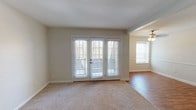 This single-story residence offers a practical and well-organized layout across two bedrooms and two bathrooms. The living area is a standout feature, showcasing soft carpeting and a set of French doors fitted with horizontal blinds that allow natural light to filter in while providing a connection to the outdoors. Adjacent to the living space, the dining area transitions to warm hardwood-style flooring and is illuminated by a ceiling fan with integrated lighting. A window on the dining room wall adds additional natural light and visual openness to this combined living-dining zone.

The kitchen is efficiently designed with white cabinetry, a double-basin stainless steel sink, light countertops, and white appliances including a range and over-the-range microwave. A set of bi-fold doors provides convenient pantry or storage access, and the hardwood-style flooring continues underfoot.

Both bedrooms are carpeted and feature ceiling fans with light fixtures. One bedroom includes a window with a view to the outside, while both rooms offer a calm, neutral palette. The primary bathroom includes a wide vanity with a large mirror and ample counter space, while the secondary bathroom features a compact vanity with an integrated sink, a medicine cabinet mirror, and a tub-shower combination. Clean, neutral tones are carried consistently throughout the entire space.