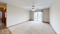 Located at 281 Country Village Dr in Smyrna, Tennessee, this 2-bedroom, 2-bathroom residence offers a functional and comfortable single-floor layout. The open kitchen and living area serves as the heart of the home, with the kitchen featuring wood-trimmed white cabinetry, light countertops, wood-look vinyl flooring, and white appliances including a range, dishwasher, and refrigerator. A chandelier adds a touch of warmth overhead. The living room is carpeted and bright, highlighted by a ceiling fan with light fixture and a sliding glass door that opens to a balcony with outdoor views. Both bedrooms are carpeted and finished with warm wood-toned trim and doors. The primary bedroom offers a generous footprint with direct access to an en-suite bathroom and a dedicated closet. The second bedroom features a closet with bifold doors and a window that brings in natural light. The two bathrooms are well-appointed: one includes a walk-in shower with wood-look flooring, while the other offers a full shower-tub combination, both featuring vanities with warm wood accents. Neutral wall tones throughout create a clean, cohesive aesthetic suitable for a variety of decor styles.