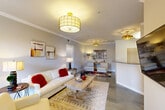 Located at 10720 Linkwood Ct in Baton Rouge, Louisiana, this well-appointed 2-bedroom, 2-bathroom single-story home offers a thoughtfully designed layout with refined finishes throughout. The open-concept living and dining area immediately impresses with its polished concrete floors, crisp crown molding, and stylish gold-accented drum pendant lighting. Large windows allow natural light to fill the space, creating a warm and inviting ambiance. The living room flows seamlessly toward the dining area, which features a marble-top table and tasteful wall art. The kitchen is outfitted with white cabinetry, granite-style countertops, and a full suite of appliances, offering both functionality and a clean aesthetic. The primary bedroom is generously sized, featuring vaulted ceilings, a ceiling fan, and a large window with views of the surrounding greenery. The second bedroom is versatile, currently utilized as a home office, and also benefits from natural light and elevated ceilings. Both bathrooms are clean and functional, with one showcasing wood-look flooring and a tub-shower combination. Additional highlights include four closets for ample storage and an in-unit laundry area. The overall design balances modern sensibility with comfortable livability throughout.