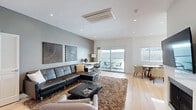 Located at 1818 Thayer Ave in the heart of West Los Angeles, this contemporary 3-bedroom, 2-bathroom home delivers a clean, modern aesthetic across a single thoughtfully designed floor. Light hardwood flooring flows throughout, complementing the crisp white walls and recessed lighting that give the space a bright, airy feel.

The open-concept living and dining area serves as the centerpiece of the home, featuring a fireplace with a wall-mounted TV, a ceiling-mounted HVAC unit, and large sliding glass doors that open to a private balcony — ideal for indoor-outdoor living. The living area also includes a dedicated workspace nook.

The kitchen is outfitted with high-gloss white cabinetry, a full suite of stainless steel appliances, and tile flooring, offering both style and functionality. A dedicated laundry area adds everyday convenience.

The generously sized primary bedroom features a bold dark accent wall, light hardwood floors, a large sliding-door closet, and direct access to an en-suite bathroom. Additional bedrooms are bright and well-proportioned, each with natural light and wall-mounted TVs.

Both bathrooms are finished with large-format beige tile, modern wall-hung toilets, and sleek glass-enclosed showers — one with a soaking tub combo. Five closets throughout the home provide ample storage.