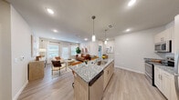 This thoughtfully designed single-floor residence offers 1 bedroom, 2 bathrooms, an office, and a well-organized layout that maximizes comfort and functionality. The open-concept kitchen and living area serves as the heart of the home, featuring a large granite-topped island with an undermount sink, pendant lighting, light wood cabinetry, and stainless steel appliances. The island accommodates bar seating, making it ideal for casual dining and entertaining. The living room is bright and welcoming, with large windows and a glass-panel door that invite abundant natural light. Light wood-look flooring flows throughout the main areas, complementing the neutral, warm color palette. The dedicated office provides a quiet workspace, complete with carpeted flooring and ample room for a full desk setup. The primary bedroom is a comfortable retreat, carpeted and cozy, with space for a full suite of furniture. Both bathrooms echo the kitchen's design language, featuring granite vanity countertops and light wood cabinetry; the primary bath includes an integrated closet with built-in shelving. A separate closet provides additional storage. Throughout the space, recessed lighting, clean lines, and a cohesive modern aesthetic create a polished yet inviting atmosphere.