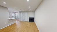 This thoughtfully designed 1-bedroom, 1-bathroom residence offers a cohesive and modern living experience across a single floor. The open living area is anchored by a sleek corner fireplace with dark tile surround and is finished with warm-toned laminate hardwood flooring that extends throughout the main areas. Recessed lighting illuminates the space, while a ceiling fan and window with blinds add comfort and natural light. Vertical blinds lead to what appears to be a patio or balcony access, enhancing the sense of openness.

The kitchen and dining area flow seamlessly together, showcasing striking marble-look quartz countertops, white shaker cabinetry with matte black hardware, a subway tile backsplash, and stainless steel appliances. A peninsula with an undermount sink serves as both a functional workspace and a casual dining divider.

The bedroom features plush carpeting, recessed lighting, and a closet for storage. The bathroom is a standout, with large-format marble-look wall tile in the tub/shower surround, a herringbone mosaic niche, a navy blue vanity with quartz countertop, and matte black fixtures. A dedicated laundry room with wire shelving and full-size washer and dryer completes this well-equipped home.