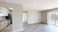 Located at Woodbridge Place in Evansville, Indiana, this single-floor residence presents a clean, contemporary aesthetic carried consistently throughout its interior. Light gray wood-look flooring runs seamlessly across the living areas and bedrooms, complementing the neutral greige wall tones that lend the space a bright, cohesive feel.

The living area is generously proportioned, featuring a sliding glass door that introduces natural light and provides access to the outdoors. A ceiling fan overhead adds both function and a subtle design detail. The open layout connects naturally to adjacent rooms, supporting easy movement throughout the floor plan.

The kitchen is designed for efficiency, featuring a galley-style configuration with white shaker cabinetry, dark gray laminate countertops, a tile backsplash, and stainless steel appliances including a refrigerator, dishwasher, and range. Ample upper and lower cabinet storage ensures practical usability.

The bedrooms are calm and well-lit, with one featuring a wide window fitted with horizontal blinds that allow filtered natural light. Each room benefits from the same consistent flooring and neutral palette.

The bathroom is neatly finished with a gray-toned vanity, dark countertop, a full tub-shower combination with a curved curtain rod, and brushed nickel hardware and grab bars throughout.