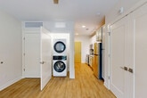 Located at 421 Broadway St in the heart of Asheville, NC, this efficiently designed single-floor studio offers a thoughtfully organized layout that maximizes every square foot. Light wood-tone flooring runs throughout the unit, creating a warm and cohesive aesthetic, while recessed lighting and a ceiling fan keep the space bright and comfortable.

The kitchen is a standout feature, outfitted with white shaker-style cabinetry, granite countertops, a textured tile backsplash, and a full suite of stainless steel appliances including a refrigerator, electric range, over-the-range microwave, and dishwasher. A stacked washer and dryer unit is conveniently integrated into the hallway area, adding practical in-unit laundry without sacrificing the overall flow of the space.

The living area is open and airy, anchored by a large window that invites natural light and offers views of surrounding greenery. A set of double doors leads to a spacious closet, providing ample storage. The bathroom features matching granite countertops, a sage-toned vanity with modern hardware, and a clean, neutral color palette with light gray walls.

Overall, the unit presents a clean, contemporary finish with efficient use of space, making it well-suited for those seeking a functional and stylish home base in downtown Asheville.