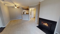 Located at 3885 Gabrielle Lane in Aurora, Illinois, this single-floor residence offers a well-designed layout that balances comfort and functionality. The living area is a standout space, featuring plush carpeting, crown molding, and a tile-surround gas fireplace that serves as a focal point. A ceiling fan overhead provides year-round comfort, while a sliding glass door floods the room with natural light and opens to a private balcony overlooking the surrounding greenery.

The kitchen is positioned adjacent to the living area in an open-concept arrangement, anchored by a breakfast bar peninsula. White cabinetry with modern hardware pairs with gray laminate countertops and stainless steel appliances, including a gas range, built-in microwave, dishwasher, and refrigerator. Hardwood flooring runs throughout the kitchen, and a separate utility area off the kitchen provides space for an in-unit washer and water heater.

The bedroom offers generous proportions with soft carpeting, neutral gray walls, and a large walk-in closet with built-in shelving. A second carpeted bedroom features a wide window with views of the outdoors. The bathroom includes a full tub and shower combination with white tile accented by a black tile border, dark tile flooring, and oil-rubbed bronze fixtures.