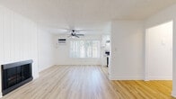 Located at 2600 W La Habra Blvd in La Habra, California, this 2-bedroom, 1-bathroom residence offers a clean, modern aesthetic across a single floor. Light wood-style flooring runs throughout the home, creating a cohesive and airy feel. The combined living and dining area serves as the heart of the home, highlighted by a classic fireplace with a sleek black surround, a ceiling fan with integrated lighting, a wall-mounted AC unit, and a large window with vertical blinds that invites natural light. The kitchen is thoughtfully updated with white shaker cabinetry featuring black hardware, quartz countertops, a herringbone tile backsplash, stainless steel gas range with overhead ventilation hood, and a dishwasher. The spacious primary bedroom includes a ceiling fan, a window, and a mirrored sliding-door closet with built-in shelving. A second bedroom provides additional flexibility, also finished with the same light wood flooring and white walls. The full bathroom is well-appointed with a white vanity, large mirror, black fixtures, and a shower-tub combination. Two closets and a hallway complete the functional layout, making efficient use of the available space throughout this bright and cleanly finished home.