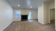 This single-story, 3-bedroom, 2-bathroom residence offers 750 square feet of thoughtfully arranged living space. The open kitchen and living room area serves as the heart of the unit, where the kitchen features dark cabinetry, white quartz countertops, stainless steel appliances including a refrigerator, range, and microwave, a tile backsplash, and wood-look luxury vinyl plank flooring. Recessed lighting illuminates both the kitchen and adjacent living room, which is anchored by a dark tile-surround fireplace and includes multiple windows and a glass door for natural light. The three carpeted bedrooms are well-proportioned, with the primary bedroom measuring 150 square feet. Bedrooms include windows with blinds, ceiling fans in select rooms, and access to a hallway and closet. The two bathrooms are finished with white tile surrounds and chrome fixtures; one features a tub/shower combo with a grab bar, while the second offers a tub/shower unit with dark vanity cabinetry and wood-look flooring. A dedicated closet and hallway add to the unit's practical layout. Neutral white walls and clean finishes throughout lend the space a fresh, move-in-ready appearance.