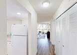 Located at 19455 NE Tenth Ave in Miami, FL, this single-floor residence offers a well-designed layout that balances comfort and functionality. Rich wood-tone flooring flows throughout the main living areas, complementing the light, neutral color palette that defines the space.

The living room is bright and inviting, featuring a large sliding glass door that opens to a private balcony overlooking lush greenery and palm trees, allowing abundant natural light to fill the room. The kitchen is efficiently designed with white shaker cabinetry, granite-look countertops, and a full suite of white appliances including a range, dishwasher, microwave, and refrigerator, all finished with recessed lighting overhead.

The bedroom is generously proportioned, featuring a ceiling fan, wood-tone flooring, and its own sliding glass door leading directly to the outdoor balcony, providing serene garden views. The bathroom is clean and bright, finished in white with tile flooring, a granite-top vanity, and a glass-enclosed shower-tub combination. A dedicated laundry area houses a stacked washer and dryer unit, adding everyday convenience. A hallway closet with louvered doors provides additional storage throughout this well-appointed Miami residence.