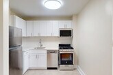 Located at 1845 Summit Place NW in Washington, DC's vibrant Adams Morgan neighborhood, Unit 704 is a thoughtfully laid-out studio residence on the seventh floor. The single-floor unit combines a living area and kitchen within a compact but efficient footprint, complemented by two bathrooms — an uncommon feature that adds notable convenience.

The living area is characterized by warm parquet hardwood flooring in a classic block pattern, which extends throughout the main space and adds a timeless aesthetic. Large windows along the exterior wall flood the room with natural light and frame pleasant views of mature, leafy trees, creating a serene indoor-outdoor connection. A double-door closet provides practical built-in storage within the living space.

The kitchen is separated from the living area and features white shaker-style cabinetry, stainless steel appliances including a gas range, dishwasher, microwave, and refrigerator, as well as light tile flooring and a single-basin sink. The clean, bright finishes give the kitchen a modern and functional feel.

The bathrooms maintain a simple, neutral palette with white tile surrounds, a tub-shower combination, and chrome fixtures, contributing to the unit's clean and well-maintained overall presentation.