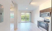 Located in Princeton, FL, this 2-bedroom, 1-bathroom unit offers a thoughtfully designed layout across a single floor. The open living area is filled with natural light, courtesy of large sliding glass doors that lead to a private balcony with views of lush greenery. Light-toned wood-style flooring and crisp white walls throughout lend the space a clean, modern aesthetic.

The kitchen is well-appointed with rich dark wood cabinetry, granite countertops, a tile backsplash, and a full suite of stainless steel appliances including a refrigerator, range, built-in microwave, and dishwasher — combining style with everyday functionality. Track lighting adds a contemporary touch to the living and kitchen areas.

Both bedrooms are bright and efficiently laid out, with the primary bedroom offering a closet with built-in shelving for organized storage. The bathroom features large-format neutral tile surrounding a full soaking tub and shower combination, paired with tile flooring for a clean, spa-like feel.

The unit also includes a dedicated laundry area and utility room, adding practical convenience. The overall ambiance is light, airy, and move-in ready, making this a functional and modern home in a verdant South Florida setting.