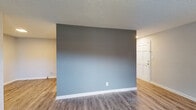 Located at 601 Chalk Level Road in Durham, NC, this single-floor unit offers a clean, updated interior with a cohesive neutral color palette throughout. The flooring consists of wood-look planks in a warm gray-brown tone, installed consistently across the living areas and bedrooms, contributing to a unified and contemporary feel.

The living area features a distinctive two-tone accent wall transitioning from charcoal gray to soft blue, adding visual interest to an otherwise understated space. A window allows natural light to filter in, and the room connects openly to adjacent areas. The textured popcorn ceilings are present throughout the unit.

The bedrooms are well-proportioned, each featuring windows that bring in natural light and views of the surrounding exterior. Closet space is available in the bedrooms, with one room featuring a reach-in closet with shelving and another with a walk-in style layout. HVAC vents are ceiling-mounted for efficient climate control.

The bathroom includes a full tub-shower combination with clean white surround walls and standard chrome fixtures. The 3D floor plan view confirms a practical, linear layout with a kitchen area, bathroom, and multiple rooms arranged efficiently across the single floor.