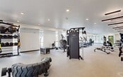 This state-of-the-art fitness center, located at 9201 N 29th Ave in Phoenix, Arizona, offers a comprehensive workout experience within its 1,910 square foot space. The facility boasts an open floor plan with high ceilings and large windows, allowing ample natural light to flood the area. The gym is equipped with a wide array of modern exercise machines, including cardio equipment, weight training stations, and functional fitness apparatus. 

A striking feature is the extensive use of mirrors along the walls, enhancing the sense of space and allowing users to monitor their form. The center is divided into distinct zones for different types of workouts, including a cardio area, a strength training section with free weights and resistance machines, and a functional fitness space featuring equipment like battle ropes and large tires.

The interior design is clean and contemporary, with a neutral color palette dominated by whites and greys. The flooring appears to be a durable, low-maintenance material suitable for high-traffic gym environments. Strategically placed recessed lighting and unique rectangular pendant lights provide excellent illumination throughout the space.

Safety and convenience features are evident, with visible emergency exits, water stations, and what appears to be climate control systems for user comfort. The layout promotes easy navigation and efficient use of space, making it an ideal environment for both individual workouts and potential group fitness classes.