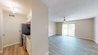 This single-floor unit offers a well-organized, open layout that maximizes both functionality and comfort. The main living area is spacious and bright, featuring light-toned luxury vinyl plank flooring throughout, a ceiling fan with light fixture, and a large sliding glass door that opens to a private balcony — allowing natural light and outdoor views to fill the room.

Adjacent to the living area, a pass-through window connects to the kitchen, creating an open, connected feel. The kitchen is equipped with stainless steel appliances including a range and microwave, white shaker-style cabinetry, a subway tile backsplash, a sink, and dark countertops that provide a clean contrast to the light finishes.

A dedicated bedroom benefits from its own ceiling fan, a generously sized window with a view of surrounding greenery, and the same consistent vinyl plank flooring found throughout the unit. A hallway with a closet offers additional storage and connects the living spaces seamlessly.

The bathroom is well-appointed with a white shaker vanity, a grey-toned countertop, an undermount sink with brushed nickel hardware, a full tub-shower combo with white tile surround, and wood-look flooring. The overall aesthetic of the unit is clean, neutral, and move-in ready, presenting a cohesive and modern living environment.